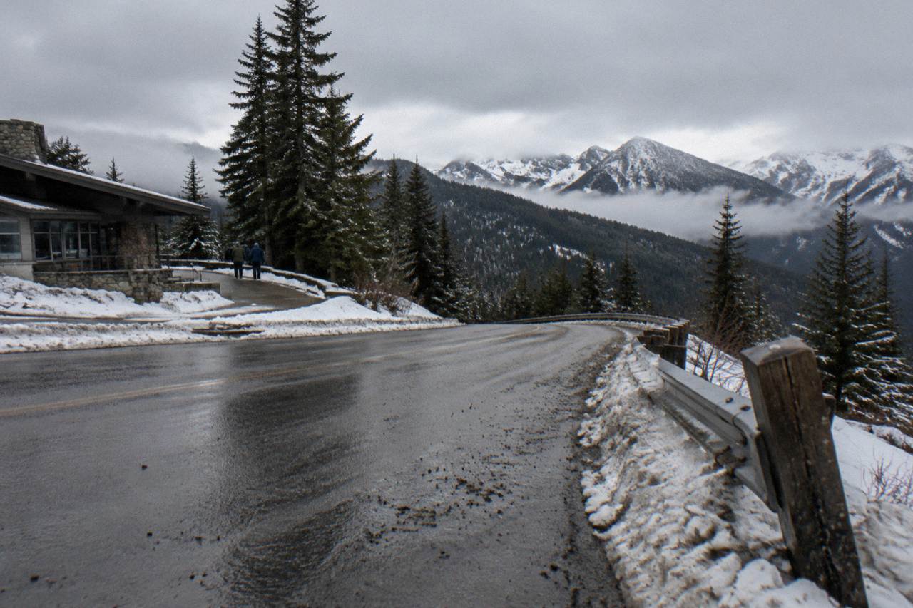 A paved mountain road curving toward forested ridges under an overcast sky