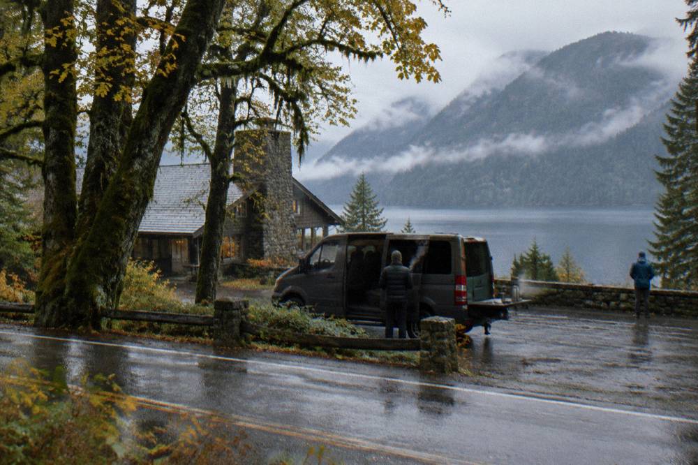A passenger van parked at a misty forest overlook along a highway.