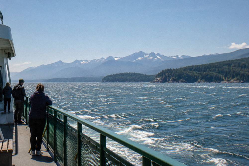 A ferry deck with mountains and open water in the distance