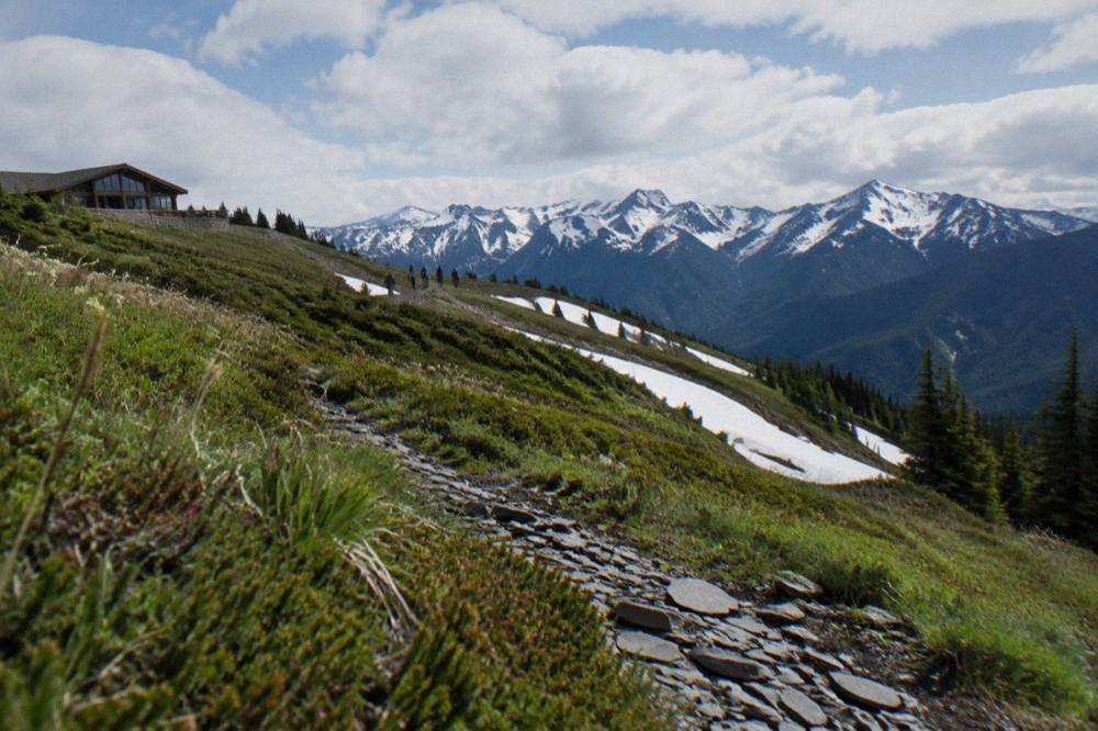 Alpine ridge meadows with distant snow peaks under scattered clouds