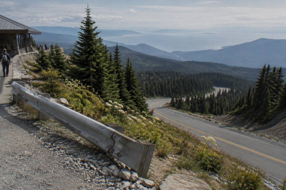 Mountain road climbing through forest toward a high ridge with views over the strait