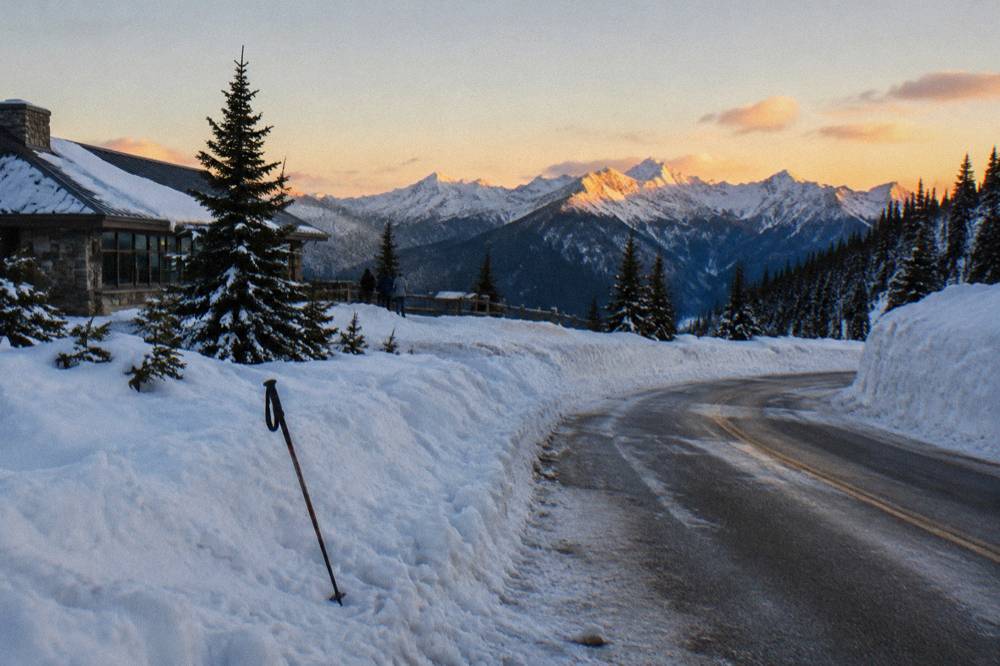 A snow-covered mountain road winding toward a frosted ridge with distant peaks