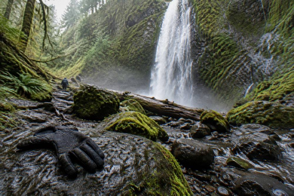 A waterfall dropping through dense mossy forest into a rocky creek