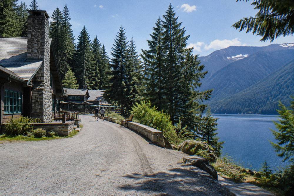 A curving highway beside a deep blue mountain lake ringed by evergreen forest