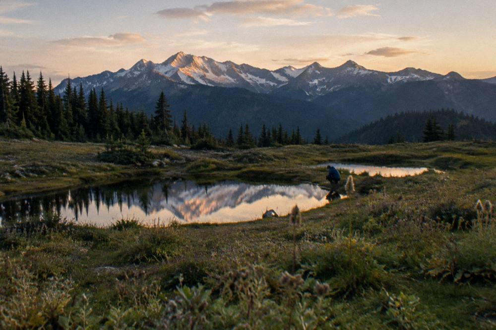Alpine meadow with small lakes below a snow-dusted ridge