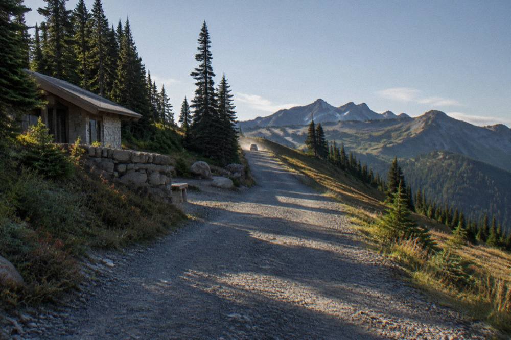 Winding mountain road climbing through forest toward an open ridge